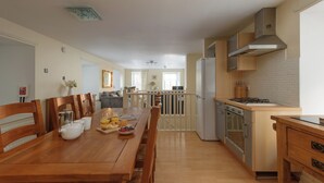 Eine geräumige Küche mit Essbereich, Holzmöbeln und Blick zum Wohnzimmer.