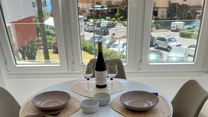 Een eettafel gedekt voor twee personen, met een fles wijn, twee glaasjes en een schaal.