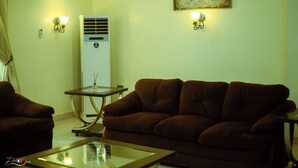 Ein Wohnzimmer mit einem braunen Sofa, einem Glastisch und einer wandmontierten Klimaanlage.