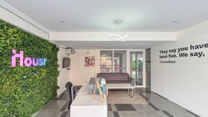A modern office space with a reception desk, a couch, a green wall with 'Housr' signage, and a motivational quote on the wall. - Housr 1 RK Sector 27 Gurgaon Golf Course (Gurugram)
