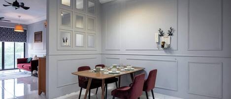 A dining area with a wooden table set for four, surrounded by red chairs. A ceiling fan and pendant light are visible above the table.