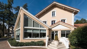 Un bâtiment à deux étages, doté d’une architecture moderne, avec de grandes fenêtres et une entrée imposante agr émentée de marches.
