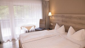 Ein Hotelzimmer mit einem großen Bett, einem kleinen Tisch, einem Sessel und einer Lampe.
