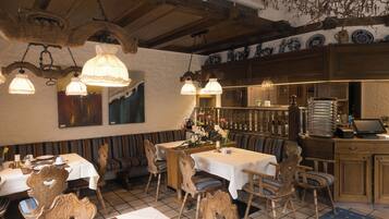 Un restaurante con mobiliario de madera, manteles blancos y lámparas colgantes.