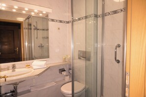 Une salle de bain moderne avec une douche à parois de verre, un lavabo avec un miroir au-dessus et des toilettes.