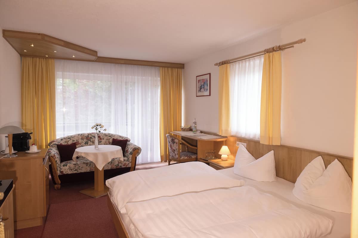 Una habitació d'hotel amb un llit, una taula de treball, una cadira i una taula petita.