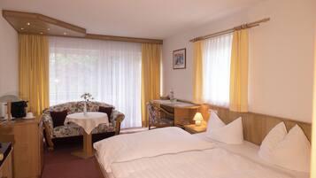 A hotel room with a bed, a desk, a chair, and a small table.