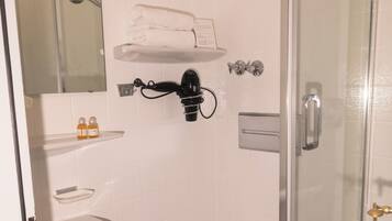 A bathroom with a glass shower enclosure, a white sink, a toilet, and a mirror above the sink.