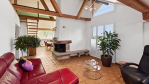 A spacious living area with a fireplace, red leather sofa, and a large potted plant.