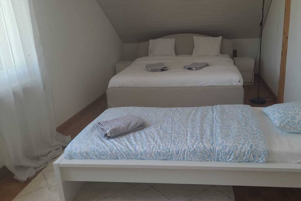 Eine kleine, einfache Unterkunft mit einem Bett, einem Nachttisch und einer Stehlampe.