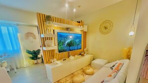Una sala de estar moderna con un televisor de pantalla plana montado en un panel de madera, un sofá blanco y una mesita de centro.