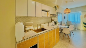 Una cocina moderna con armarios blancos, encimera de madera y un comedor con mesa y sillas.