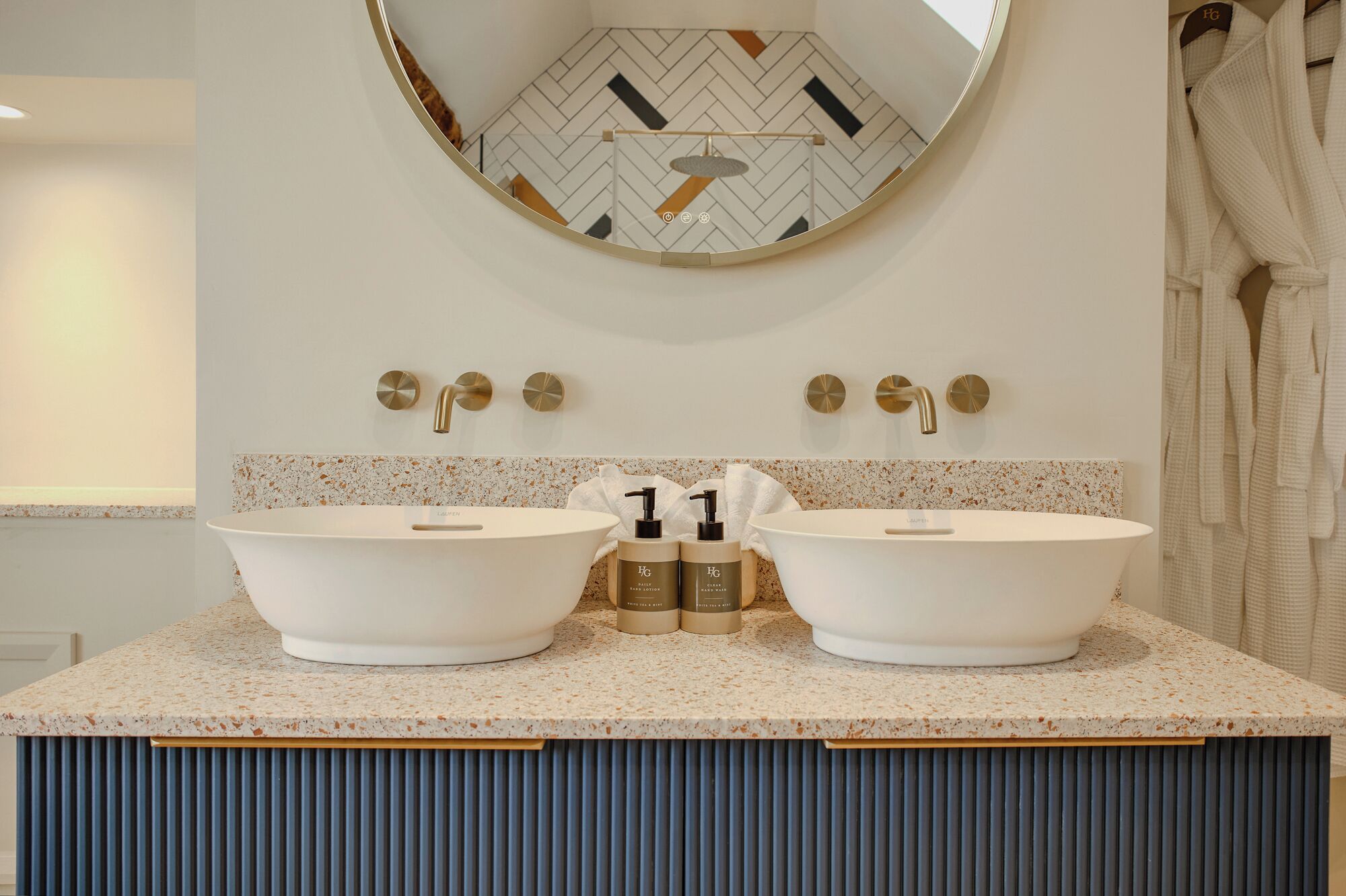 A bathroom with two sinks, a mirror, and a towel rack.