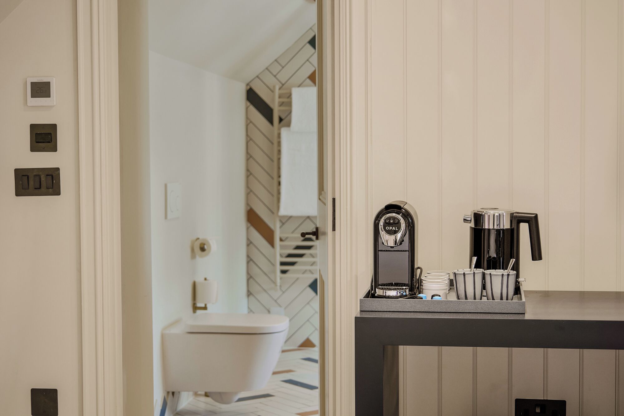 A modern bathroom with a toilet, a coffee machine, and a sink.