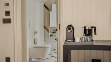 Un baño moderno con inodoro, cafetera y lavabo.