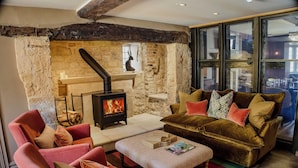 A cozy living room with a stone fireplace, a sofa, and a coffee table. - House of George W. Davies (Broadway)
