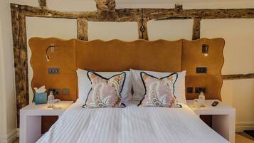 A bed with a wooden headboard, two bedside tables, and a nightstand with a lamp and a bottle.