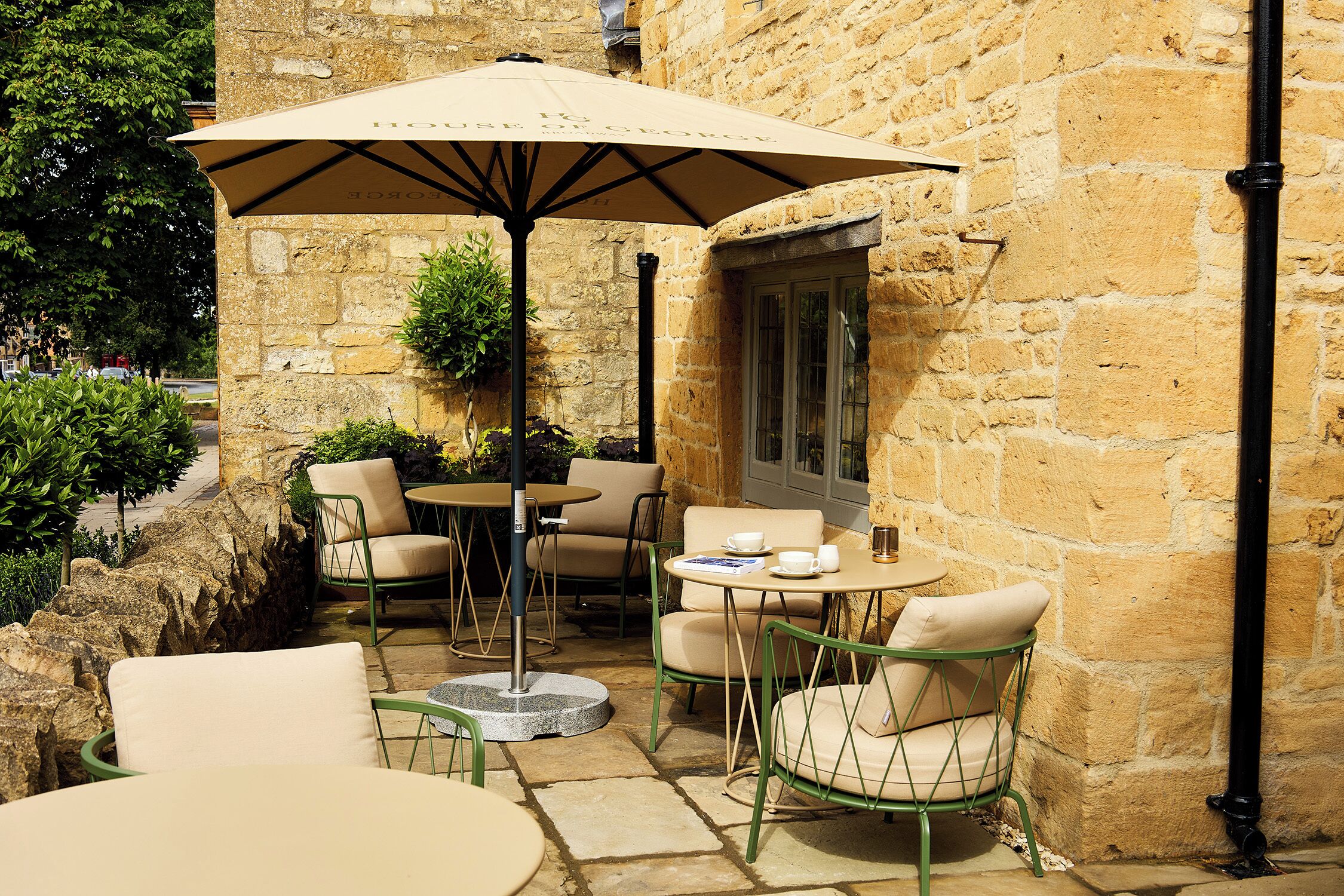 An outdoor patio with stone walls, a table with chairs, and an umbrella.