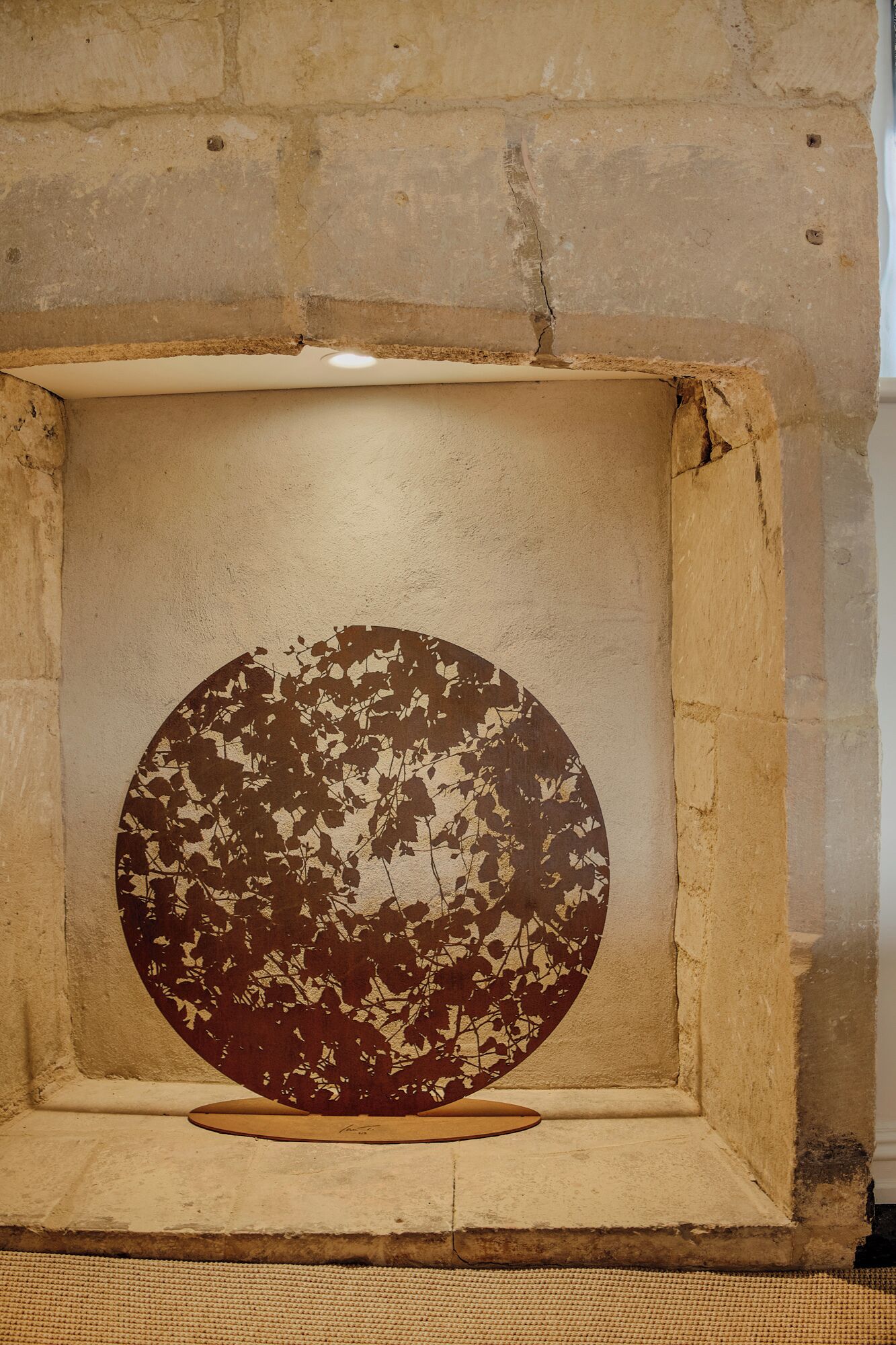 A circular object with a textured surface, placed within a square frame against a textured wall.
