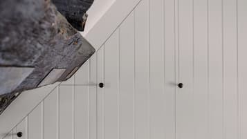 Primer plano de una pared blanca con paneles verticales y dos objetos circulares negros.