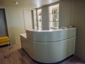 A reception desk with a counter, a bench, and shelves with toiletries. - House of George W. Davies (Broadway)