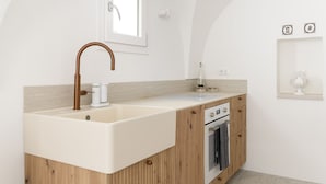 A modern kitchen with a large white sink, wooden cabinetry, a built-in oven, and a small window above the sink. - Terrazza Costa by Wonderful Italy (Ostuni)