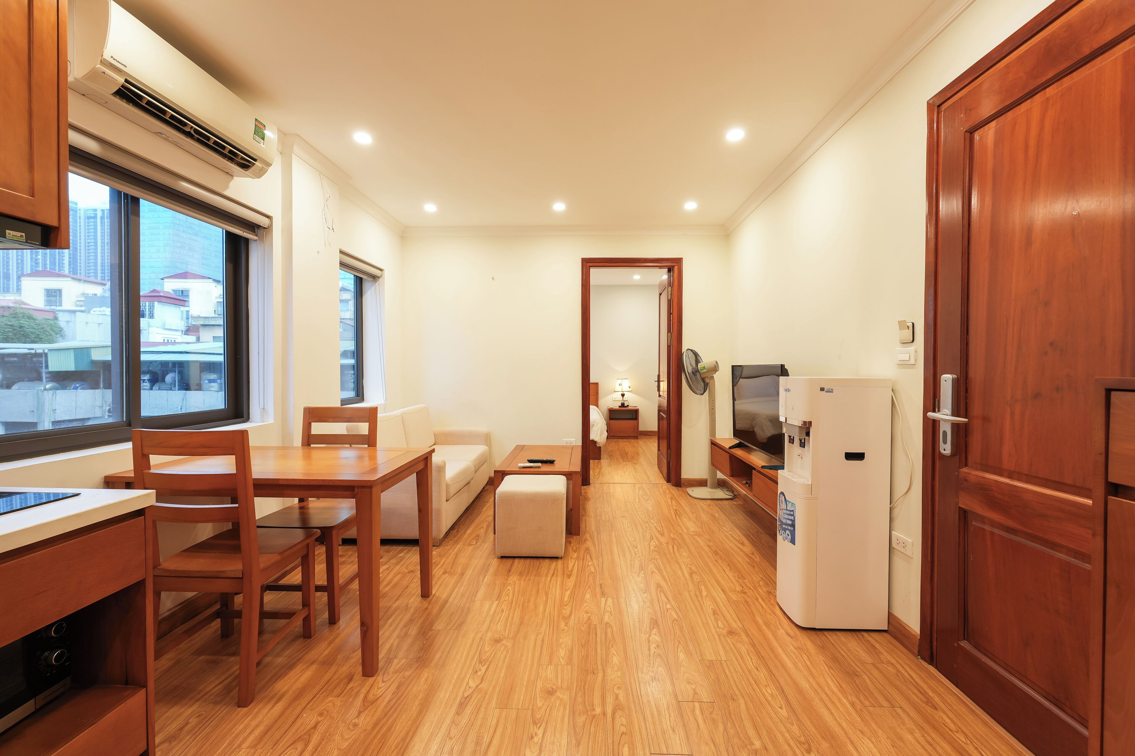 Een compacte hotelkamer met een kitchenette, een eethoek, een sofa en een televisie.