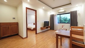 A hotel room with a wooden floor, a bed, a TV, a desk, and a window with curtains. - NINE HOUSING 68 Kim Ma Thuong (Hanoi)