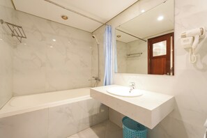 Une salle de bain moderne avec un sol en marbre, une baignoire, un lavabo et un sèche-cheveux fixé au mur.