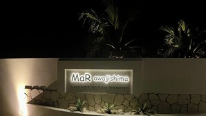 Placa do MaR aWajishima Luxury Beach Resort, com parede de pedra e plantas.