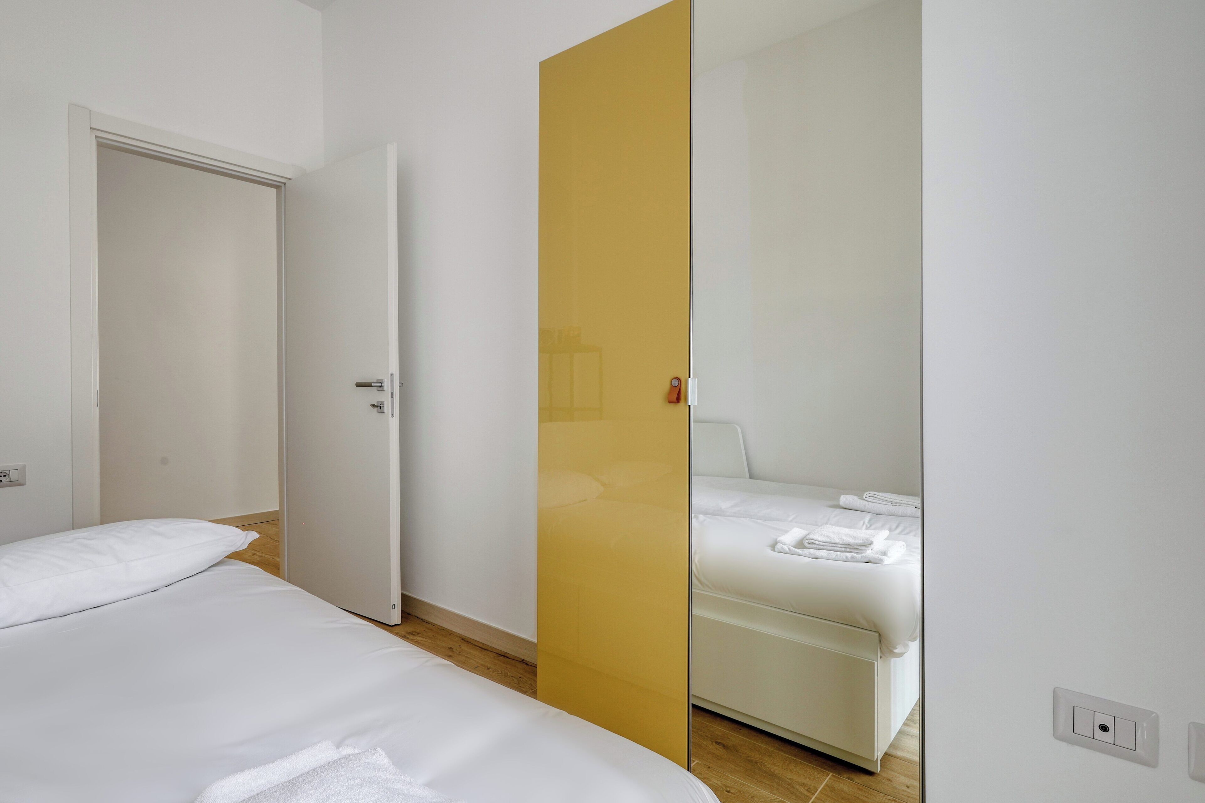 A hotel room with a bed, a bedside table, and a wardrobe.