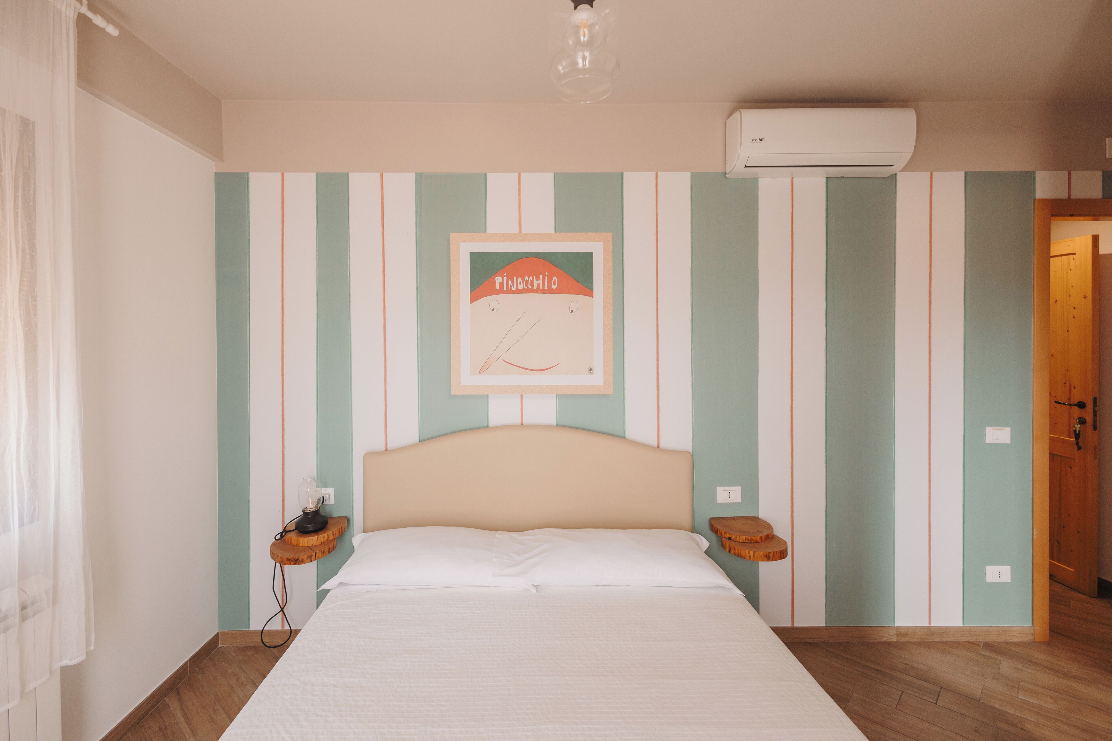 Une chambre à coucher avec un lit, une table de chevet, une horloge murale et une porte.