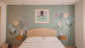 Un dormitorio con una cama, un mural floral en la pared y un cuadro enmarcado sobre la cama.