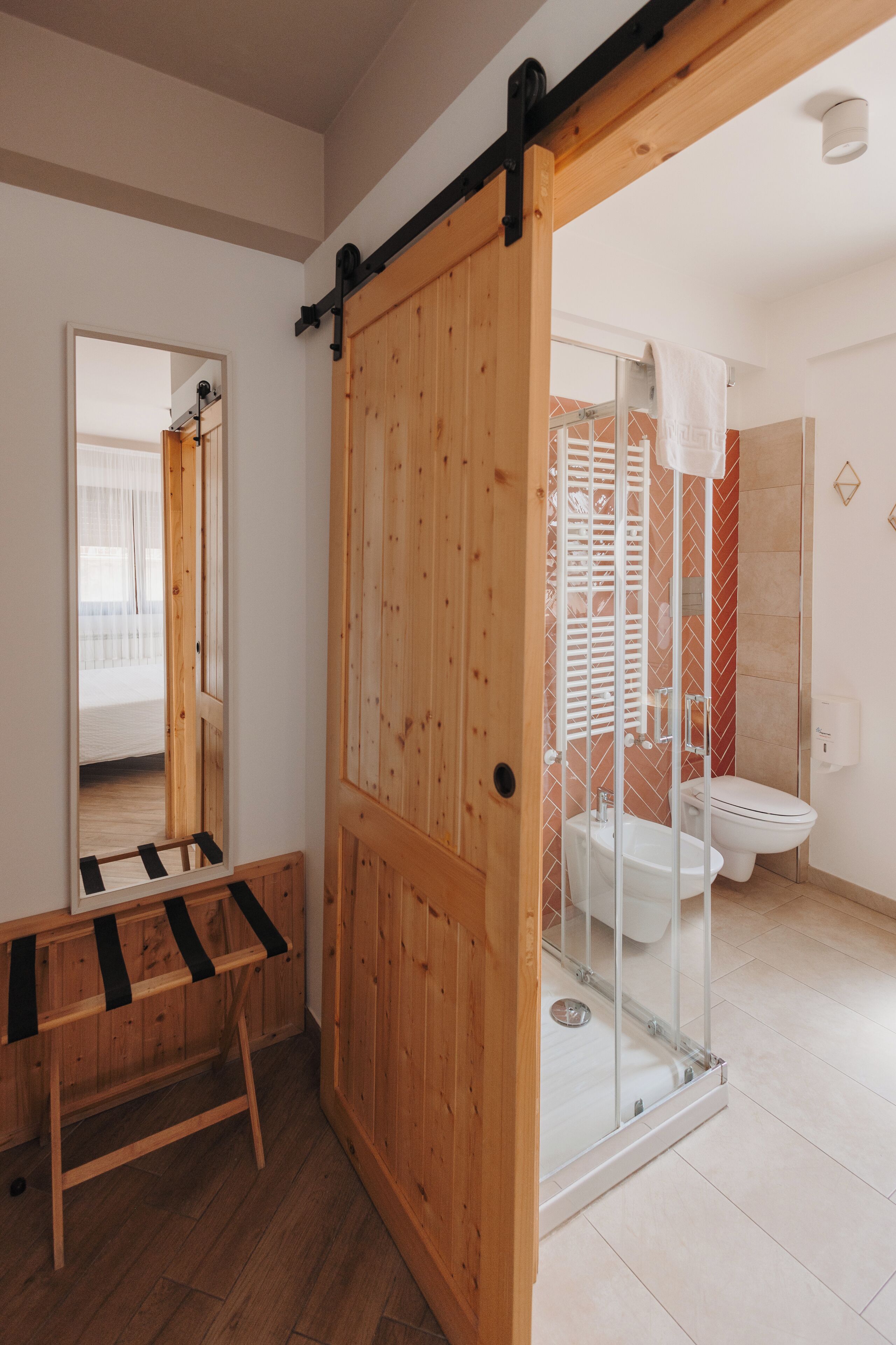 A bathroom with a wooden door, a glass shower enclosure, a toilet, and a sink.