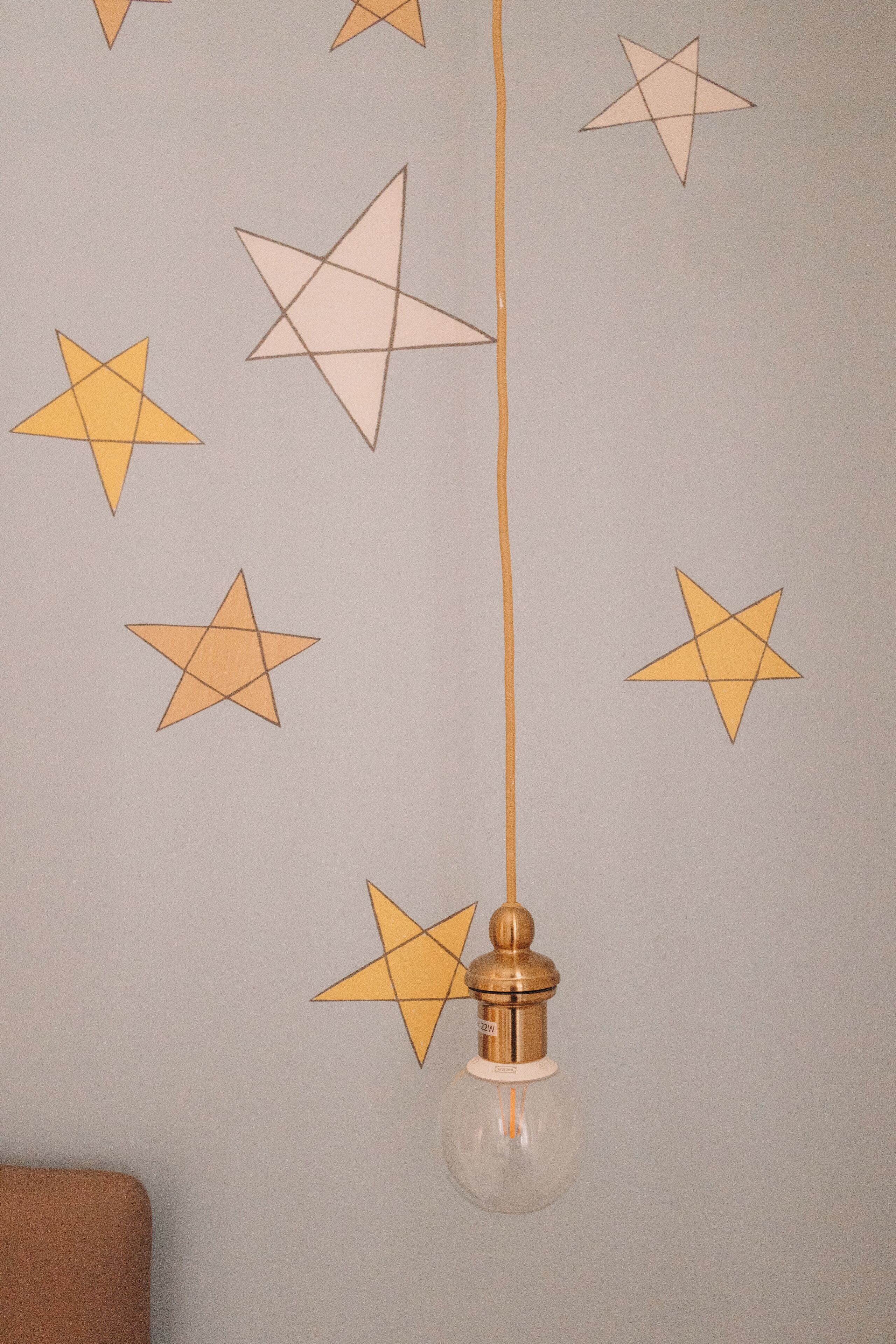 Un mur orné de motifs géométriques en forme d’étoiles et un luminaire suspendu.