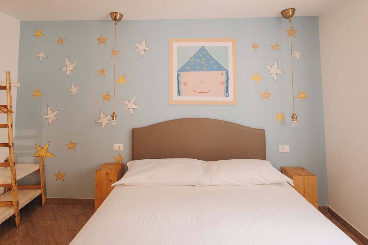 A bedroom with a bed, wooden headboard, and a wall with star decorations.