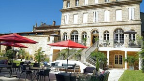 Un bâtiment en pierre doté d’une terrasse et de parasols rouges.