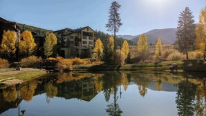A serene lakeside view with buildings, autumn trees, and a clear sky. - Peak Vistas | Walk to Trails | 4 Mins to Resort (Fraser)