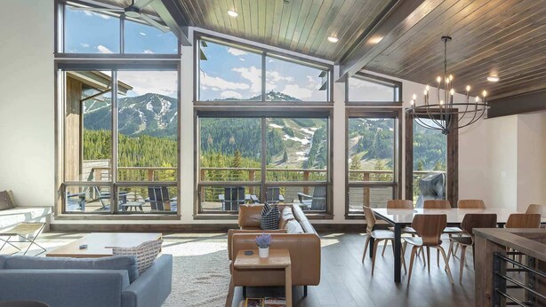 A spacious living area with large windows offering mountain views, a cozy seating area, and a dining space.