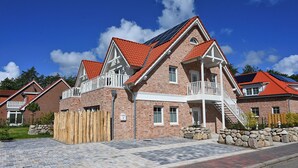 A brick house with a red roof, a balcony, and solar panels.