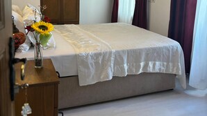 Een slaapkamer met een bed, een houten garderobe, een airconditioning en een vaas met bloemen.