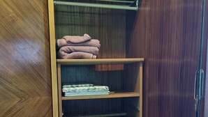 Une armoire en bois dotée de plusieurs étagères et de tiroirs, contenant des serviettes pliées et un vêtement plié.