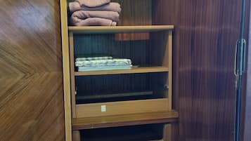 Een houten garderobe met meerdere planken en lades, met daarin opgevouwen handdoeken en een opgevouwen kledingstuk.