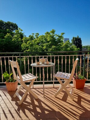 A balcony with two white lounge chairs, a small round table with a teapot and cups, and potted plants. - 950mt sea, 500mt center, apartment 120sqm 3rd floor elevator 5 beds 3 rooms (Rimini)