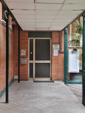 A building entrance with a metal door, a green awning, and a tiled floor. - 950 m from the sea, 500 m from downtown, 120 m² apartment on the 3rd floor with elevatoreur 5 -bed, 3-room apartment (Rimini)