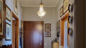 Un couloir avec une porte en bois, un banc, une chaise et un lustre.