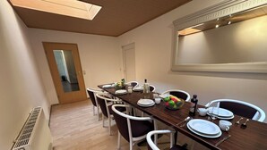 A dining area with a long table set for six, white chairs, a radiator, and a door in the background. - Modern Holiday Home with Garden and nature near Warnow (Warnow)