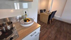 A modern kitchen with a built-in stove, a bowl of fruit, and a dining area with a table and chairs.