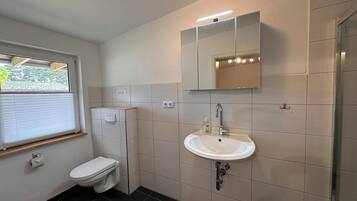 Une salle de bain équipée de toilettes, d’un lavabo et d’une douche.