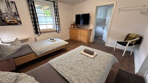 A modern, compact room with two beds, a TV, a wooden cabinet, and a chair. - Modern Holiday room with Garden and Horse Riding near Warnow (Warnow)